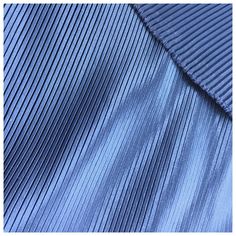 a blue pleated shirt is shown in close up view, with the bottom part showing