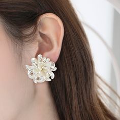 a close up of a person wearing earrings with flowers on the back of their ear