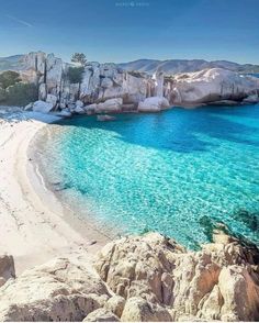 the water is crystal blue and there are rocks on the beach near the shore that look like they're floating in the ocean