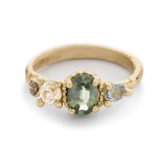 a ring with three different colored stones on the side and an oval shaped stone in the middle