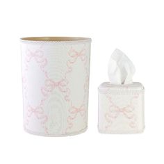 a white and pink tissue holder next to a roll of toilet paper