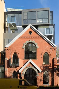 a yellow van parked in front of a brick building with windows on the top floor