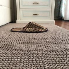 a pair of slippers sitting on top of a rug in front of a dresser