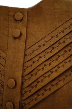 a close up of a dress with buttons on the front and back, all in brown