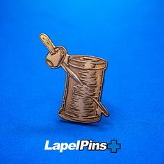 a lapel pin with a sewing needle and thread in it on a blue background