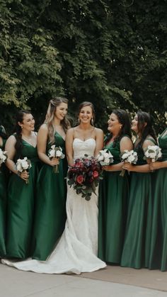 a group of women standing next to each other wearing green dresses and holding bouquets