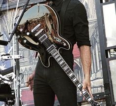 a man holding a guitar while standing next to a microphone