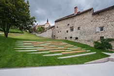 an outdoor area with steps and grass in front of a stone building on a cloudy day