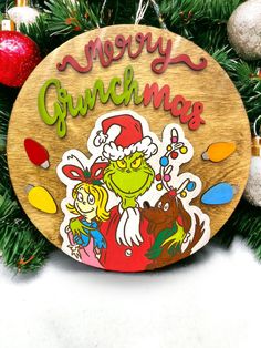 a wooden sign that says merry grinnan's on the side of a christmas tree