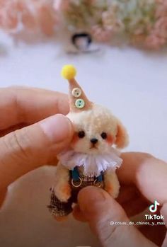 a small teddy bear with a tiny hat on it's head is being held by someone