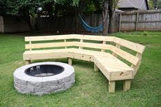 a wooden bench sitting next to a fire pit on top of a lush green field