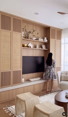 a woman standing in front of a flat screen tv next to a white couch and chair