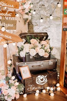 suitcases stacked on top of each other in front of a sign with flowers hanging from it