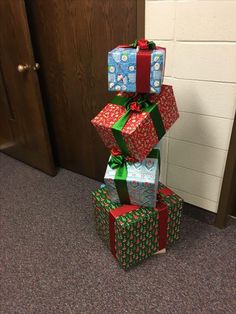 three wrapped presents stacked on top of each other in front of a door with christmas decorations