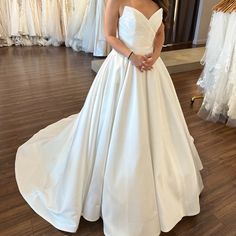 a woman in a white wedding dress standing next to a rack with dresses on it