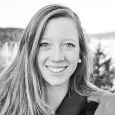 a black and white photo of a woman smiling at the camera with trees in the background