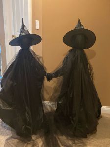 two plastic witches holding hands in front of a door