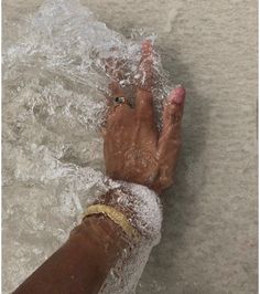 a person's hand in the water with their feet covered by sand and plastic