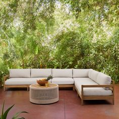 a couch and table on a patio with trees in the backgroung area