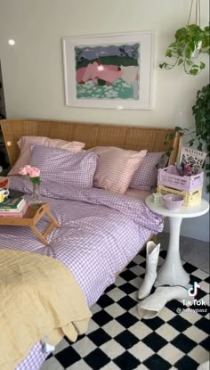 a bed with purple and white checkered sheets in a room next to a table