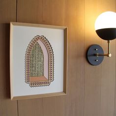 a wall mounted light next to a wooden paneled wall with a painting on it