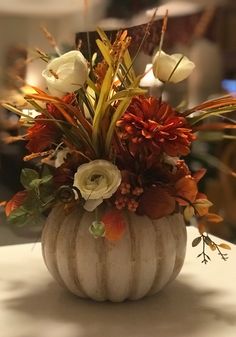 a white pumpkin filled with flowers on top of a table