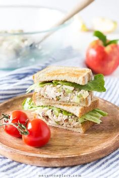 a sandwich cut in half sitting on top of a wooden cutting board next to tomatoes