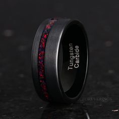 a black ring with red and blue glitter inlaying the center, on a dark surface