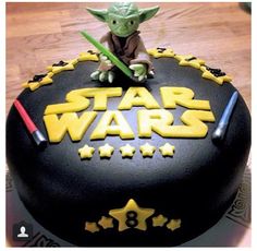 a star wars themed cake with a yoda figure on top and yellow stars around the edges