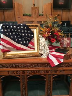 an american flag and flowers are on a table with a sign that says, this do in remembrance of me