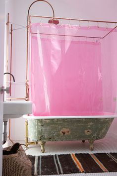 a pink bathtub in a bathroom next to a sink