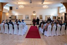 the ceremony room is decorated with white chairs and black sashes, as well as red carpet