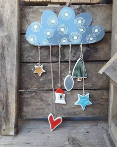 a wooden wall hanging with various decorations on it's sides and a cloud shaped like a house