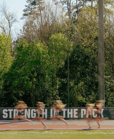 motion blur photograph of people running in front of a sign that says strength in the pack