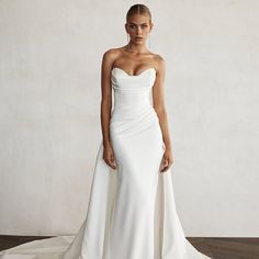 a woman in a white wedding dress posing for the camera with her hands on her hips