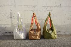 three bags sitting next to each other in front of a white wall and cement floor