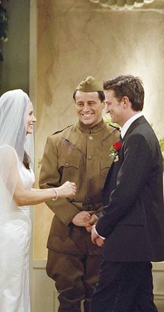 a bride and groom standing next to each other in front of a man in uniform