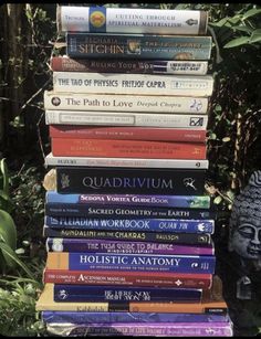 a stack of books sitting on top of each other in front of some bushes and trees