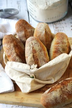 several loaves of bread in a basket on a cutting board