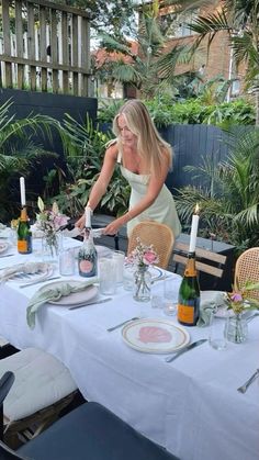 a woman is setting the table outside for dinner