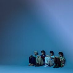 four people sitting on the ground in front of a blue background with light coming from behind them