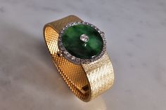 "Fine watch bracelet set with a jade donut and accented with diamonds in 18k. The donut is a deep green Omphacite jade, in parts dark and light like a globe lit. This jewel borrows the perfect finish of a Vacheron watch, its Omega straps in original burnished solid gold. More than a conversion piece, this bracelet could not have been refined to a sleeker layout. At 2cm, the donut is considered big yet its size is offset by the straps, and vice versa. The straps though wide feel made for its cent Timeless Green Jewelry For Evening, Timeless Green Evening Jewelry, Luxury Jade Bracelets For Formal Occasions, Luxury Formal Jade Bracelets, Elegant Green Diamond Watch For Formal Occasions, Fine Jade Jewelry For Formal Occasions, Luxury Green Diamond Watch For Formal Occasions, Green Luxury Diamond Watch For Formal Occasions, Luxury Jade Jewelry