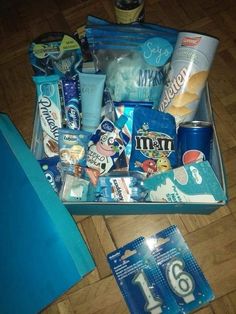 an open suitcase filled with lots of different items on top of a wooden floor next to a blue bag