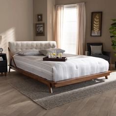 a white bed sitting on top of a wooden floor next to a chair and table