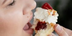 a woman eating a piece of cake with whipped cream and raspberries on top