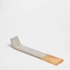 a white and gold toothbrush on a white surface with a wooden handle in the foreground