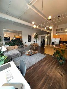 a living room filled with furniture next to a kitchen and dining room table in front of an open floor plan