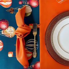 an orange place setting with silverware, napkins and other decorations on the table