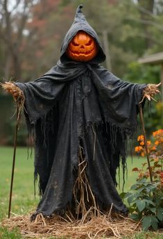 a scarecrow with a pumpkin on its head and two brooms in his hands