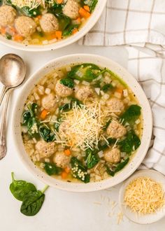 two bowls of soup with meatballs, spinach and parmesan cheese on the side